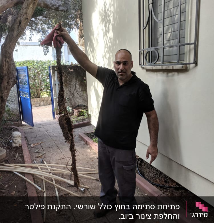 אדם מחזיק שורש סתום ליד צינורות וכלים